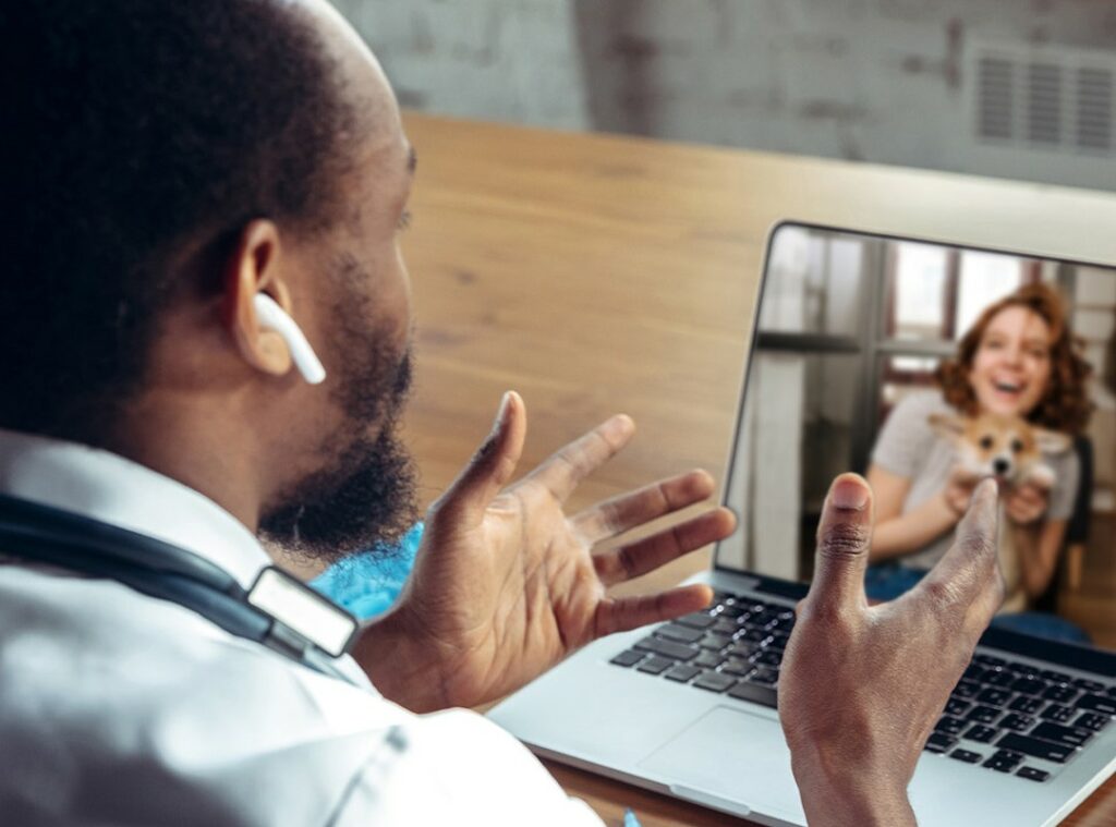 Veterinário realizando teleconsulta com tutor e paciente canino via videoconferência